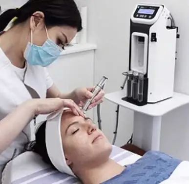 Client receiving a facial treatment with a hydrabrasion device